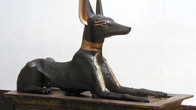 The gilded wooden statue of a reclining black jackal, representing Anubis, mounted on the portable shrine chest found guarding the Treasury doorway in Tutankhamun's tomb, now in the Egyptian Museum, Cairo.