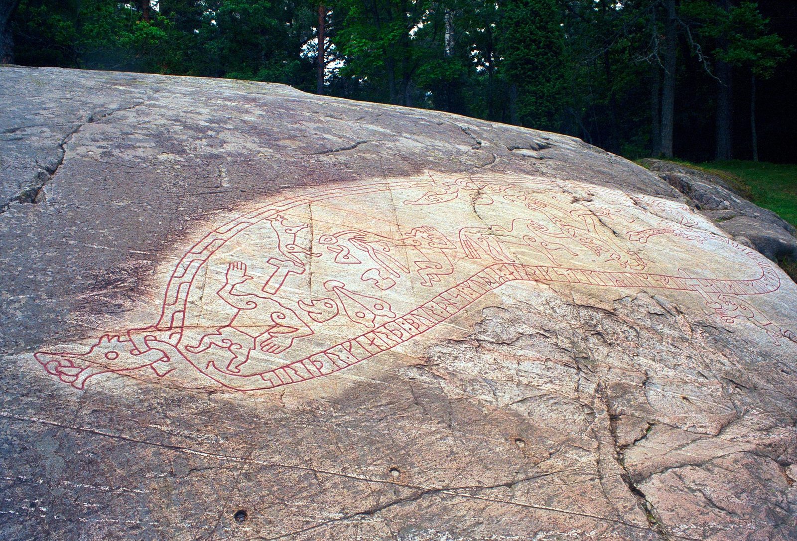 The Ramsund carving in Sodermanland, Sweden, an 11th-century rock engraving depicting Sigurd stabbing Fafnir from a pit, roasting the dragon's heart, and loading treasure onto his horse Grani.