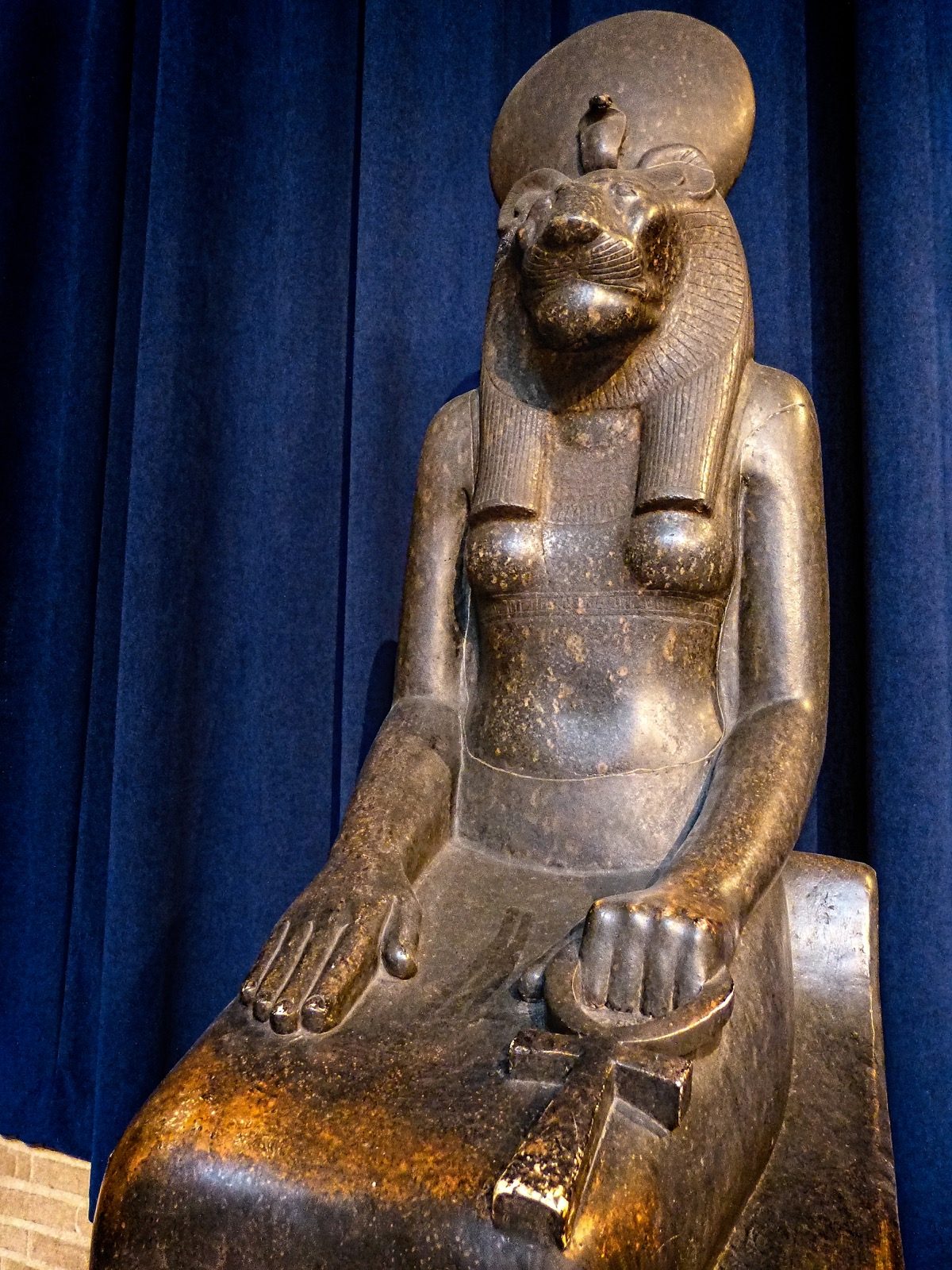Black granite statue of the lioness-headed goddess Sekhmet, seated and holding an ankh, excavated at the Ramesseum in Thebes and dated to the late 18th Dynasty, roughly 1405 to 1367 BC.