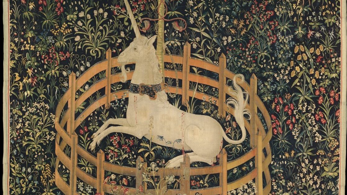 The final panel of The Hunt of the Unicorn tapestry series, showing a white unicorn resting inside a low circular fence in a flowering meadow, chained loosely to a pomegranate tree.